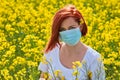 A girl in a medical mask in a field with flowers, protects herself from an allergy to pollen from plants. Coronavirus concept Royalty Free Stock Photo