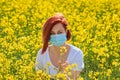 A girl in a medical mask in a field with flowers, protects herself from an allergy to pollen from plants. Coronavirus concept Royalty Free Stock Photo