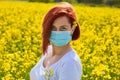 A girl in a medical mask in a field with flowers, protects herself from an allergy to pollen from plants. Coronavirus concept Royalty Free Stock Photo