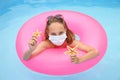 Girl with medical mask on her face in pool
