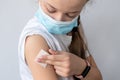 Girl in a medical mask holds cotton wool on her hand after the injection. The concept of medicine Royalty Free Stock Photo