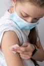 girl in a medical mask holds cotton wool on her hand after the injection. The concept of vaccination Royalty Free Stock Photo