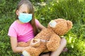 A girl in a medical mask plays doctor with a toy bear. Royalty Free Stock Photo