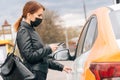 Girl in medical mask rents car for a trip to the hospital. The concept of noncash payment on the mobile app Royalty Free Stock Photo