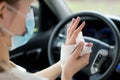 Girl in a medical mask rubs her hands with an antiseptic wipe in a car