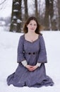 Girl in medieval dress sitting in snow