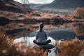 A girl meditates in a lotus position sitting on a stone on the shore of a mountain lake. Generative AI Royalty Free Stock Photo