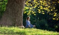 Girl meditates sitting on the grass under a maple tree in autumn Royalty Free Stock Photo