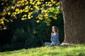 Girl meditates sitting on the grass under a maple tree in autumn Royalty Free Stock Photo