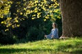 Girl meditates sitting on the grass under a maple tree in autumn Royalty Free Stock Photo