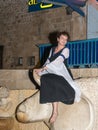 A girl - a member of the Knights of Jerusalem club, dressed in the traditional costume of a medieval lady, sits on a bull statue a Royalty Free Stock Photo