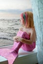 Girl-mermaid sits on the window