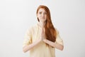 Girl messed up and beg for forgiveness. Studio shot of gloomy upset redhead woman worrying, holding hands in pray