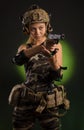 The girl in military airsoft clothes poses with a gun in her hands on a dark background