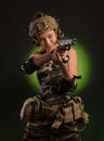 The girl in military airsoft clothes poses with a gun in her hands on a dark background