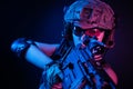 The girl in military overalls airsoft posing with a gun in his hands on a dark background in the haze in neon light Royalty Free Stock Photo