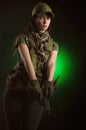 The girl in military special clothes posing with a gun in his hands on a dark background in the haze