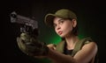 The girl in military special clothes posing with a gun in his hands on a dark background in the haze