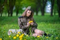 Girl in military uniform sits in a field on grass holding a bouquet Royalty Free Stock Photo