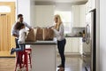 Girl and mixed race parents unpack shopping bags in kitchen