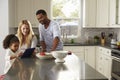 Girl and mixed race parents use tablet computer in kitchen Royalty Free Stock Photo