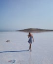 A girl model walks along the expanse of the water of a salt lake.