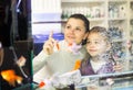 Girl with mother behind glass aquarium choosing fish Royalty Free Stock Photo