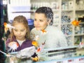Girl with mother behind glass aquarium choosing fish Royalty Free Stock Photo