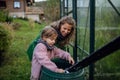 Girl and mother scooping rainwater from barell under downspout. Concept of water conservation in garden.