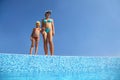 Girl with mother stand on skirting of pool