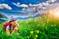 Girl in mountain meadow blowing flower
