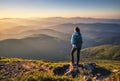 Girl on mountain peak looking at beautiful mountains at sunset