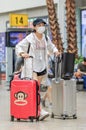Girl with mouth cap and suitcase at Beijing Railway Station South, China