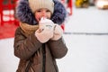 Girl with mug with snow, candy cane and inscription Merry and Bright in her hands outdoor in warm clothes in winter at festive