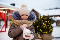 Girl with mug with snow, candy cane and inscription Merry and Bright in her hands outdoor in warm clothes in winter at festive