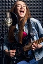 Girl musician in recording studio playing electric guitar and singing in mic Royalty Free Stock Photo