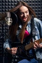 Girl musician in recording studio playing electric guitar and singing in mic Royalty Free Stock Photo