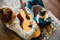 Girl musician sits on couch and plays guitar. Cat sits on mistress& x27;s lap. Playing musical instrument for pet. Top Royalty Free Stock Photo