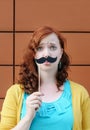 Girl with mustache party accessory Royalty Free Stock Photo