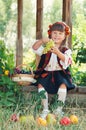 Girl in the national Ukrainian costume sitting in the garden with fruit