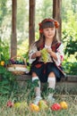 Girl in the national Ukrainian costume sitting in the garden with fruit