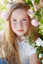 Girl on the nature of a rose. Beautiful red-haired girl near roses.