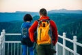 Girl and man in a blue jacket with a hood and a city backpack in the Adygea mountains, Russia