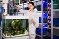 Girl with net and watering can is going catch young small fish from aquarium in aquarium shop