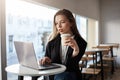 Girl never lives home without laptop. Indoor portrait of good-looking modern woman in cafe, drinking coffee while