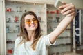 Girl never lives home without smartphone, Stylish european brunette trying on sunglasses while taking selfie on phone