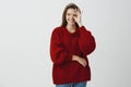 Girl never stops looking after her boyfriend. Confident joyful caucasian woman in loose red sweater, showing okay or