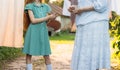 Girl next to an elderly woman. granddaughter helps her grandmother. a girl in a green dress is holding clothespins for wet clothes Royalty Free Stock Photo