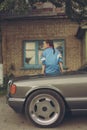 Girl in the nineties sitting on hood of car Royalty Free Stock Photo