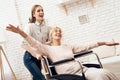 Girl is nursing elderly woman at home. Girl is riding woman in wheelchair. Woman feels like flying. Royalty Free Stock Photo